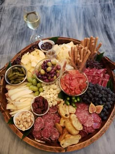 a wooden platter filled with different types of cheeses, meats and crackers