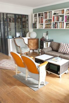 a living room filled with furniture and bookshelves on the wall next to each other