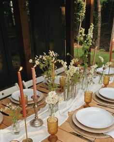 a table set with candles, plates and flowers in vases on top of it