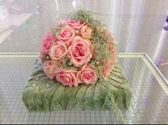 a bouquet of pink roses sitting on top of a piece of green cloth next to a window