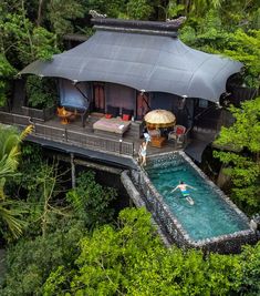 an aerial view of a house with a pool in the foreground and two people swimming