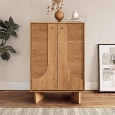 a wooden cabinet sitting on top of a hard wood floor next to a potted plant