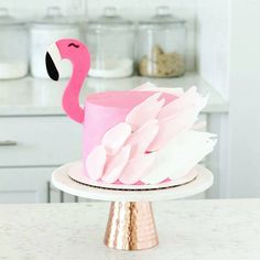 a pink flamingo cake sitting on top of a white plate next to a counter