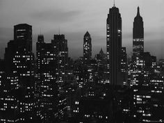 black and white cityscape with skyscrapers lit up in the dark night sky