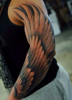 a man with a tattoo on his arm that has an angel wing design on it