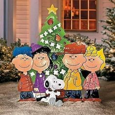 a group of cartoon characters standing next to a christmas tree in front of a house