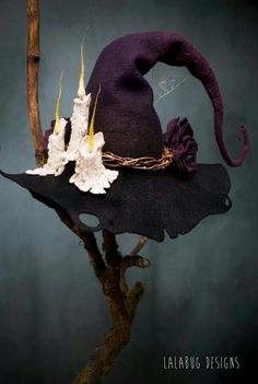 a purple hat with white flowers on it sitting on top of a tree branch in front of a dark background