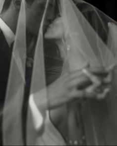 black and white photograph of bride and groom under veil