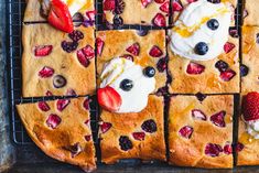 a cake with strawberries and blueberries on it is sitting on a cooling rack