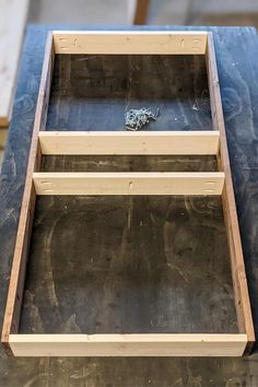 an empty wooden box sitting on top of a blue table with some wood in it