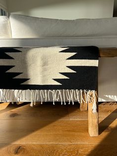 a black and white blanket sitting on top of a wooden floor next to a couch