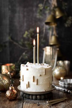 a white cake sitting on top of a wooden table next to christmas ornaments and candles