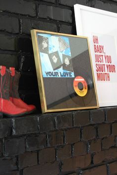 a brick wall with some framed pictures and boots on the ledge next to it,