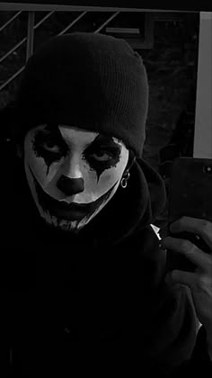 a man dressed in clown makeup holding a cell phone