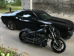 a black sports car and a motorcycle parked next to each other in front of a building