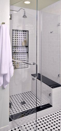 a black and white tiled bathroom with glass shower door, towel hanging on the wall