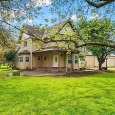 a large house sitting in the middle of a lush green field next to a tree