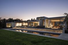 an exterior view of a modern house at dusk with water and grass in the foreground