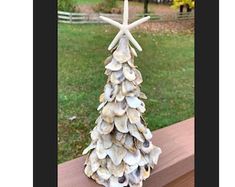 a christmas tree made out of seashells and starfish on a wooden bench