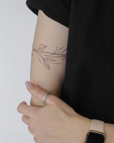 a woman's arm with a leaf tattoo on the left side of her arm