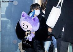 a person wearing a purple cat costume and holding a cell phone in their hand while walking through an airport