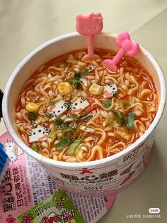 a cup filled with noodles and dices on top of a table