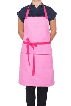 a woman wearing an apron and smiling at the camera with her hands on her hips