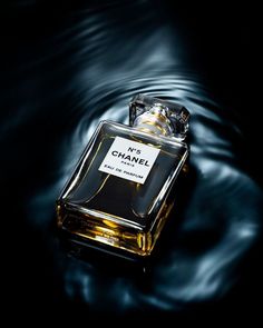 a bottle of chanel no 5 perfume sitting on top of a black liquid covered surface