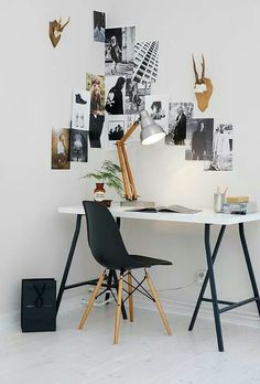 a white desk topped with a laptop computer next to a lamp and pictures on the wall