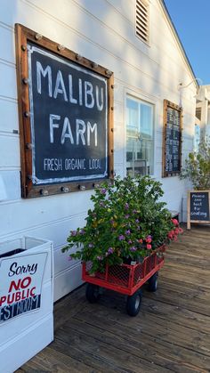 a red wagon filled with flowers sitting next to a sign on the side of a building