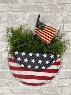 an american flag in a potted planter on a brick wall with a small us flag sticking out of it