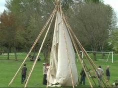 people standing around a teepee in the grass