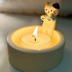 a small candle with a cat figurine on it