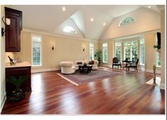 a living room with hard wood floors and white furniture in the center, along with high vaulted ceilings