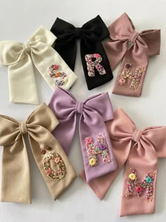 six different colored bows with the letter m on each side and flowers in the middle