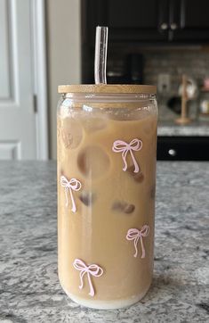 a drink in a glass with pink bows on the lid sitting on a kitchen counter