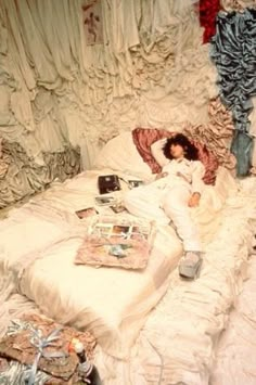 a woman laying on top of a bed covered in white sheets and ruffles