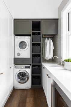 a washer and dryer are in the corner of this laundry room with white cabinets