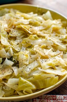 a yellow bowl filled with cabbage and grated parmesan cheese