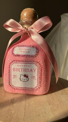 a hello kitty bottle with a pink bow around it's neck sitting on a wooden table