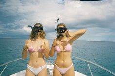 two women in bikinis on a boat with snorkeld masks giving thumbs up