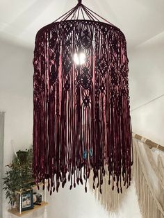 a red chandelier hanging from the ceiling in a room with white walls and stairs