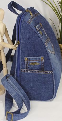 a doll is standing next to a denim bag with straps on the front and side