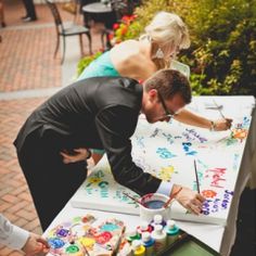 a man and woman are painting on a table