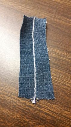 a piece of denim with white stitching on top of a wooden table next to a pair of scissors