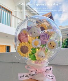 a hand holding a clear ball filled with lots of small stuffed animals and daisies