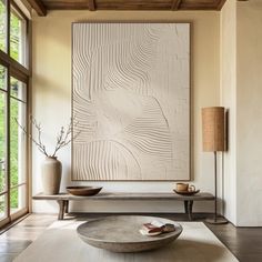 a living room with a large painting on the wall next to a coffee table and two vases