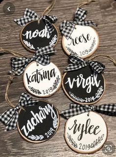 four decorated cookies with black and white plaid ribbon tied around them on top of a wooden table