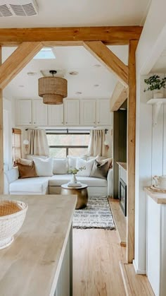 a living room and kitchen area in a mobile home with wood beams on the ceiling