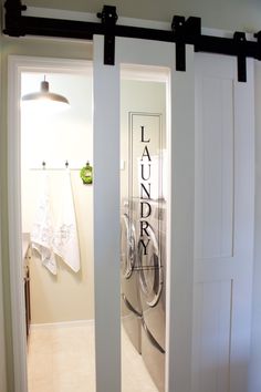 an open door leading to a laundry room with white walls and black metal bars on the doors